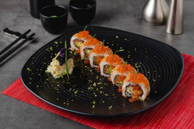 Suşi seti, siyah taştan bir tabakta çeşitli ürünler. Bulanık arkaplan ve seçici odak