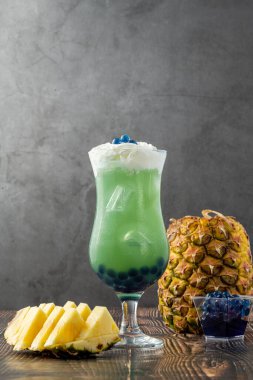 Koyu arkaplanda cam bardakta meyveli baloncuk çayı.