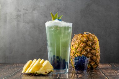 Koyu arkaplanda cam bardakta meyveli baloncuk çayı.