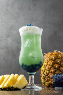 Koyu arkaplanda cam bardakta meyveli baloncuk çayı.