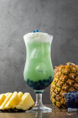 Koyu arkaplanda cam bardakta meyveli baloncuk çayı.