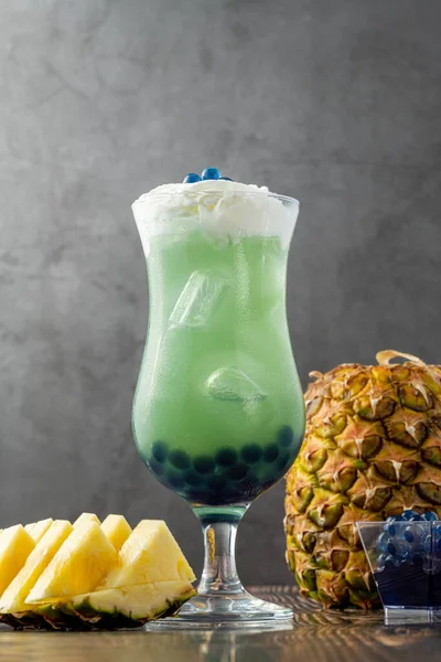 Koyu arkaplanda cam bardakta meyveli baloncuk çayı.