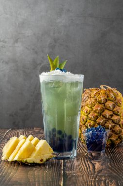 Koyu arkaplanda cam bardakta meyveli baloncuk çayı.