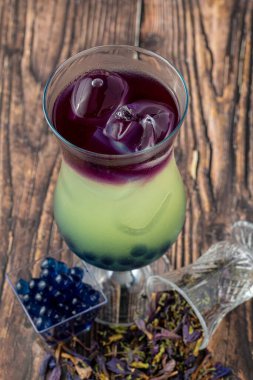 Koyu arkaplanda cam bardakta meyveli baloncuk çayı.