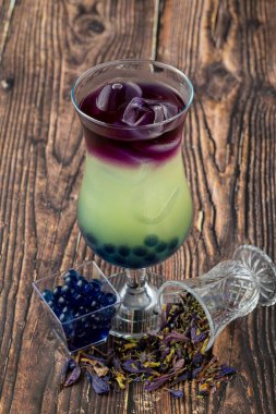 Koyu arkaplanda cam bardakta meyveli baloncuk çayı.