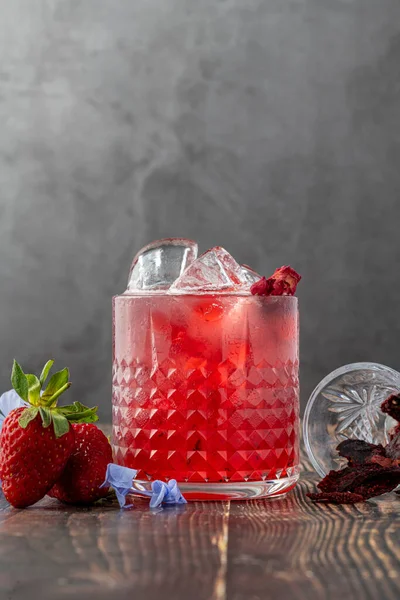 Iced cold strawberry tea with slices of dried strawberries on wooden table