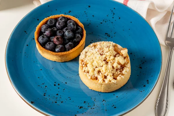 Freshly baked single portion blueberry and apple pie on a blue porcelain plate