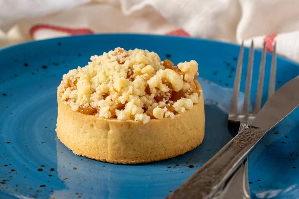 Freshly baked single portion apple pie on a blue porcelain plate