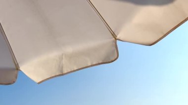 Beach umbrella seen from below in the blue sky. Looking up from the bottom