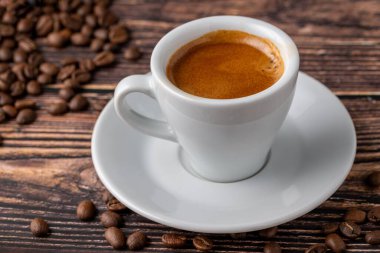 Taze espresso kahvesi, ahşap masada kahve çekirdekleri ile süslenmiş.