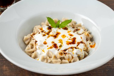 Tahta masadaki beyaz tabakta Kayseri ravioli veya Kayseri Mantisi.