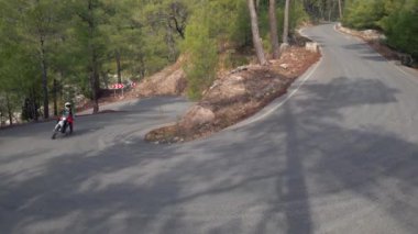 Enduro motosikleti yeşil orman ve dağ boyunca kırsal yolda sürüyor.