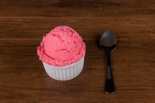 右側にデザートスプーン付きの白い鍋で提供される赤い色のアイスクリームのボール — ストック写真