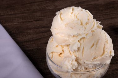 Beautiful white cream flavored ice cream. Served in the glass pot with white cloth on the left.