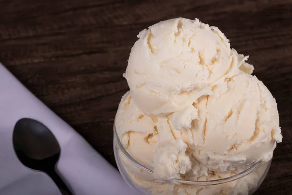 Tasty white cream flavored ice cream. Served in a glass pot. spoon over white napkin on the left. Ice Cream and Gelateria .