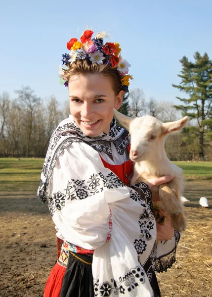 The smiling girl in folk costume with little lamb — Stock Photo, Image
