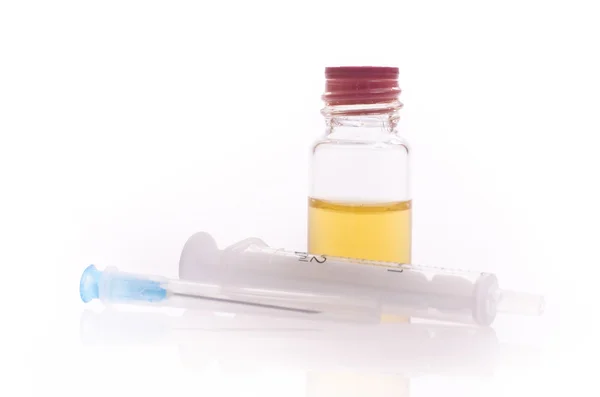 A liquid-filled syringe and a bottle of liquid — Stock Photo, Image