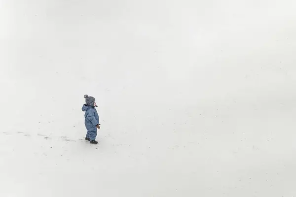 一个身穿蓝色冬衣的小男孩站在雪地上 — 图库照片