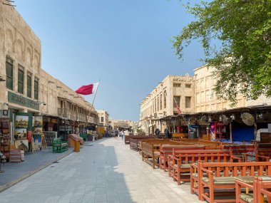 Doha, Qatar  October 5, 2019: Old town Souq Waqif with Qatari flag against blue sky.