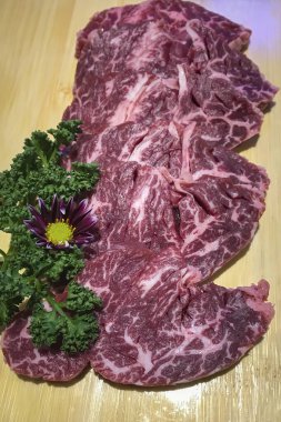 Wagyu bifteği dilimleri tahtadan bir tahtanın üzerinde servis edilir.
