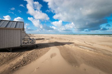 Hollanda, Kijkduin 'deki Kuzey Denizi sahilindeki kumsal kulübelerinin manzarası bulutlu mavi gökyüzüne karşı.