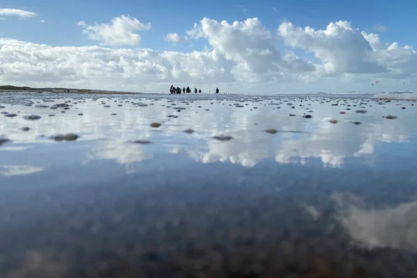 Vista Baixo Ângulo Pessoas Andando Uma Praia Com Reflexo Nuvens — Fotografia de Stock