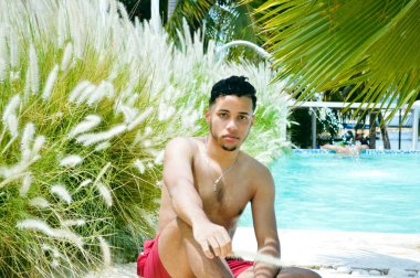 Havuz kenarındaki adam kameraya bakıyor.