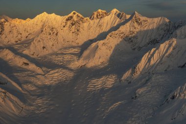 Alaska 'nın iç kesimlerindeki Alaska Sıradağlarında gün batımı karla kaplı tepelerde parlıyor.