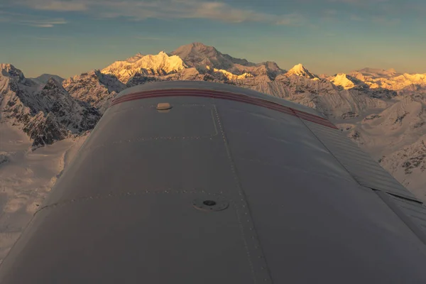 Aerial view at sunset of Denali and Alaska Range with airplane wing of Piper Cherokee Six