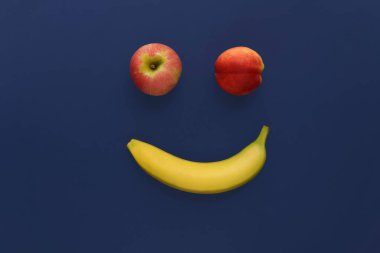 Mavi arka planda olgun meyvelerden yapılmış neşeli bir yüz..