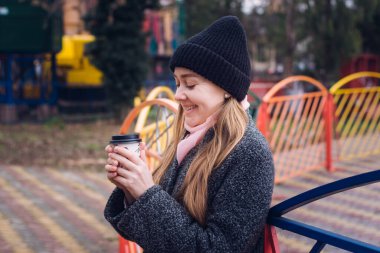 Side view of beautiful young woman with cup of hot coffee in hands