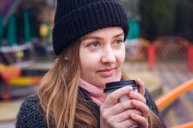 Side view of beautiful woman with cup of hot coffee in hands