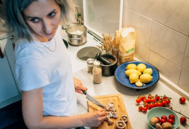 Bir kadın yemek pişirirken arkasını kollar..