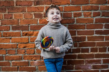 Little boy making silly faces with a giant lollipop