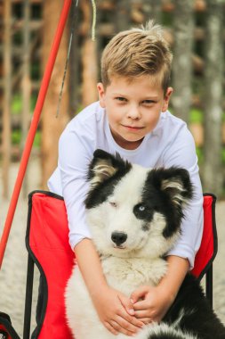 Beyaz elbiseli çocuk pofuduk köpeğe sarılıyor.