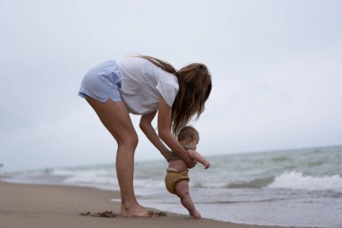 Bebek kumsalda ilk kez annesiyle birlikte kuma dokunuyor.