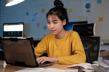 ofiste dizüstü bilgisayarda çalışan genç kadın