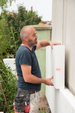 İnşaat işçisi evin duvarına blok yapıştırıyor.