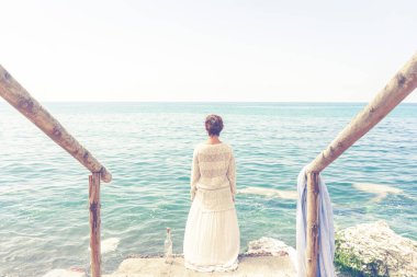 Turist şişede bir mesajla denize bakıyor.