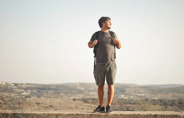 Young Man Backpacker Looks Panorama — Stockfoto