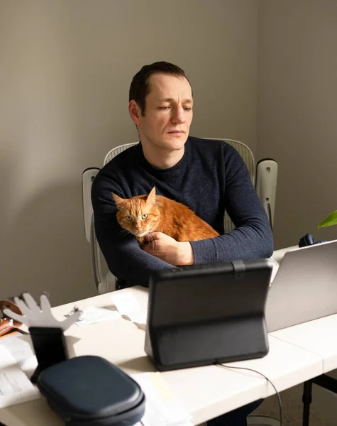 男人在家里干活 腿上抱着一只生姜猫 — 图库照片