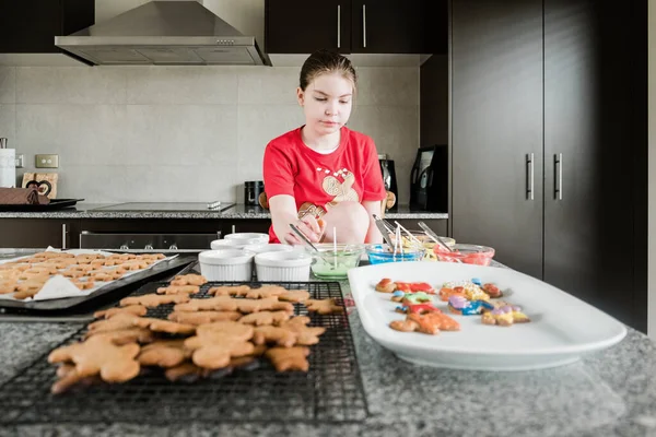 女の子は台所でジンジャーブレッドクッキーを飾る — ストック写真
