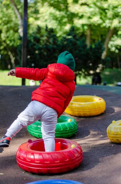 Мальчик Красной Куртке Прыгает Через Цветные Шины — стоковое фото