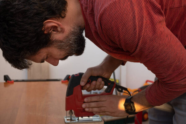 молодой человек с помощью плотницких электроинструментов