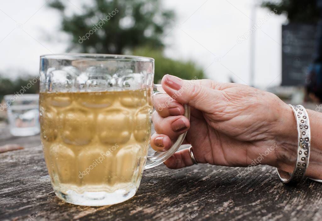 woman's hand holding a pint glass with cider in outside