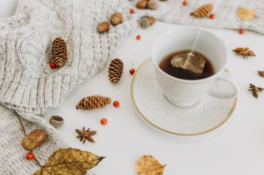 Beyaz arka planda çay poşeti ve yapraklı beyaz çay fincanı.,