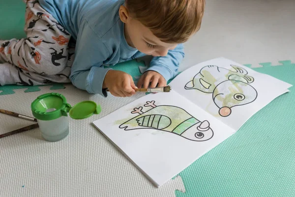 小男孩儿用画笔在水册上画鸽子的颜色 — 图库照片