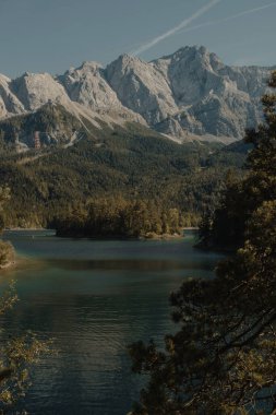 Göl, ağaçlar ve dağ zirveleri