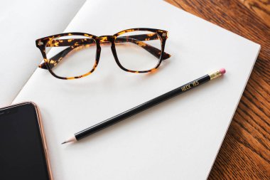 Boş Not Defteri Üzerinde Gözlükler, iPhone ve Motivasyonel Kalem