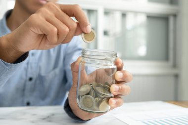 İş adamı para biriktirme konsepti. El ele tutuşan bozuk paralar, sürahi bardaklar.